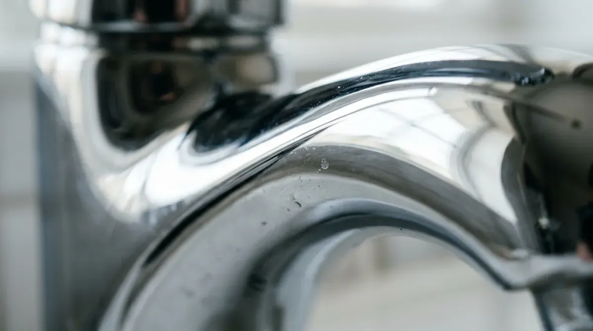 A macro texture shot of gleaming chrome faucet curves with soft reflections, crisp light